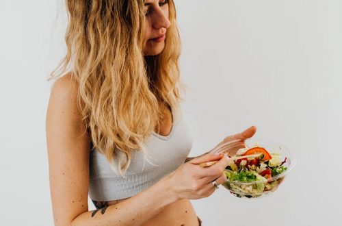 A caucasian woman in a sports bra enjoying a fresh salad, embodying healthy eating and lifestyle.
