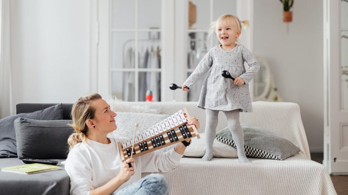 A mother and daughter bond through music at home, playing joyful melodies.