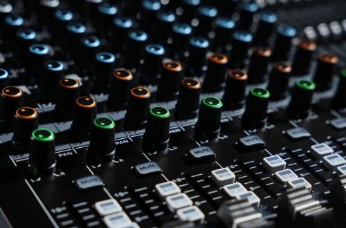 Detailed view of an audio mixing console with colorful lights in a professional studio setting.