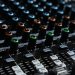 Detailed view of an audio mixing console with colorful lights in a professional studio setting.